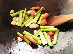 ウインナーを炒めているフライパンに小松菜の茎部分を入れる。