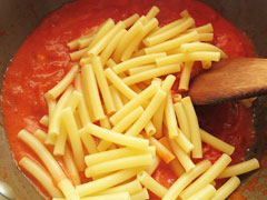 トマトソースを煮込んでいる鍋に、茹でたマカロニを入れる。