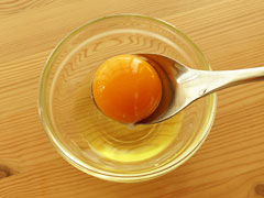小皿に割り入れた生卵の卵黄をスプーンですくう。