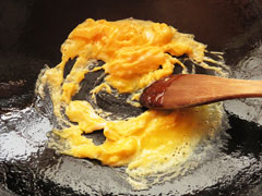 フライパンでかき混ぜながら炒り卵を作る。