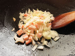 ひき肉を炒めたフライパンに、切り分けた玉ねぎとにんにく、ナルトを入れる。