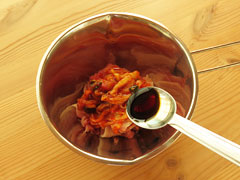 豚肉とキムチの入ったボウルに醤油を加える。