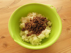 ごはんの入ったボウルに炒めたひき肉を油ごと入れる。