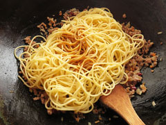 具を炒めているフライパンに茹でたスパゲティと味付け用のたれを入れる。