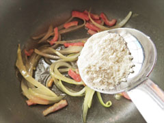 ベーコンと玉ねぎを炒めている鍋に、小麦粉を加える。