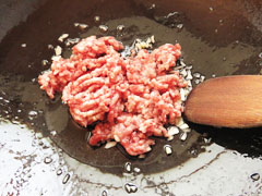 にんにくを炒めているフライパンに豚ひき肉を入れる。