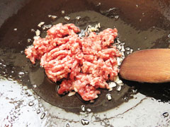 にんにくを炒めているフライパンに豚ひき肉を入れる。