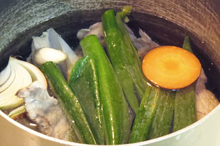 下処理した鶏がら、ネギの青いところ、生姜、にんにく、野菜くず、酒、たっぷりの水を入れた鍋。
