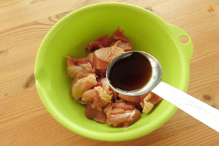 切り分けた鶏もも肉の入ったボウルに、混ぜ合わせた調味料を加える。