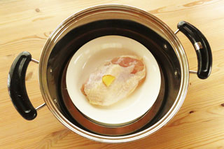 鶏胸肉を置いた皿を鍋に入れる。