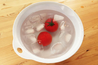 氷の入った冷水につけているトマト2個。