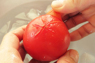 湯がいたトマトの皮のめくれた切れ込みから、皮をむく。