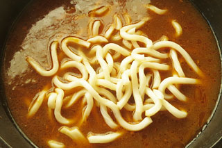 カレーうどんのつゆを煮込んでいる鍋に、チルドのうどんを入れる。