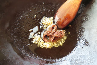 オリーブオイルで炒めているにんにくにアンチョビをくわえる。