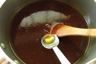 鍋で煮込んでいるラーメンスープにごま油をくわえる。