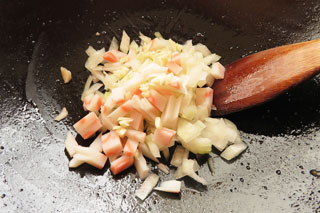 ひき肉を炒めたフライパンに、切り分けた玉ねぎとにんにく、ナルトを入れる。