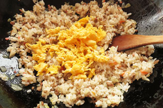 ごはんを炒めているフライパンに、炒り卵と味付け用のたれを入れる。