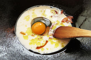 ベーコンを炒めたフライパンに牛乳と卵、パルメザンチーズ、インスタントラーメンの粉末スープを入れる。
