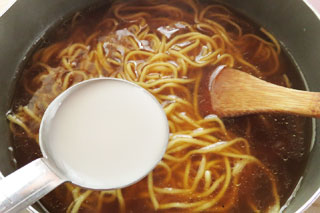 カレーラーメンを煮込んでいる鍋に水溶き片栗粉をくわえる。