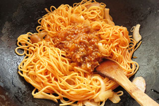ケチャップをからめて炒めたスパゲティに、残りミートソースをくわえる。