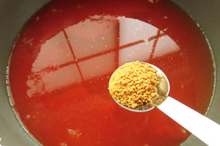 トマトジュースと水を注いだ鍋にコンソメをくわえる。