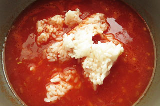 トマト雑炊のスープを煮込んでいる鍋にごはんを入れる。