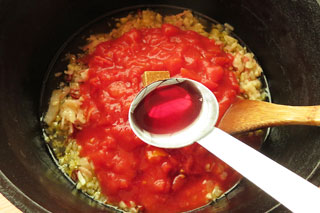 トマト缶の中身をくわえた鍋に赤ワインを入れる。