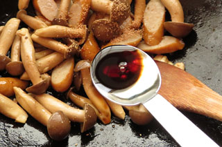 ハタケシメジとウインナーソーセージを炒めているフライパンに醤油を入れる。