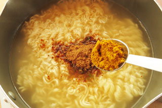 インスタントラーメンをゆでている鍋にカレー粉を入れる。