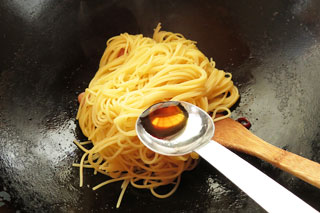 ウインナーソーセージを炒めているフライパンにゆでたスパゲティを入れる。
