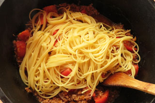 フレッシュトマトのミートソースの入った鍋にゆでたスパゲティを入れる。