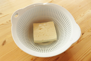 ざるに木綿豆腐を入れて水を切る。
