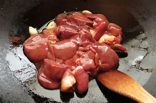 にんにくと鷹の爪を炒めているフライパンに、鶏レバーをたれごと入れる。