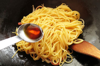 カニカマを炒めているフライパンにゆでたスパゲティを入れる。