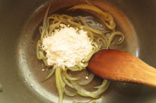 玉ねぎを炒めている鍋に小麦粉を入れる。
