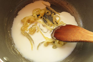 玉ねぎと小麦粉を炒めている鍋に牛乳を注ぐ。