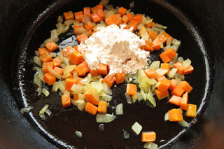 玉ねぎとにんじんを炒めている鍋に小麦粉をくわえる。