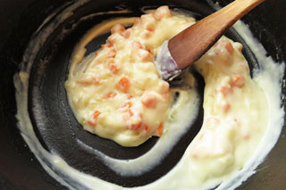 玉ねぎとにんじんを炒めている鍋に牛乳を注いでかき混ぜる。