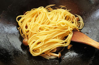 具を炒めているフライパンにゆでたスパゲティを入れる。