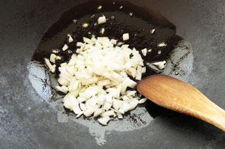 にんにくを炒めているフライパンに玉ねぎを入れる。