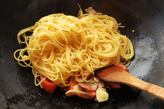 生トマトを炒めているフライパンにゆでたスパゲティを入れる。