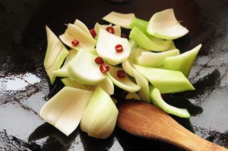 にんにくを炒めているフライパンに、チンゲンサイの茎と鷹の爪をくわえる。