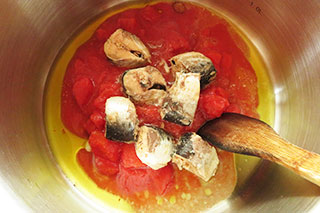 にんにくと鷹の爪を炒めている鍋にいわし缶とトマト缶を入れる