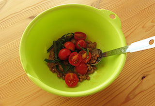 かきまぜた納豆の入ったボウルに、切り分けたミニトマトとしその葉を入れる。