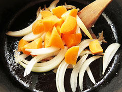 ベーコンを炒めている鍋に玉ねぎとにんじんを入れる。
