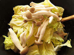 白菜の芯と鶏胸肉を炒めている鍋に、白菜の葉としめじ、白ワインを入れる。